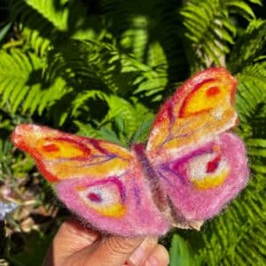 Vlinder van vilt op stukje schors